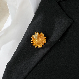Elegant gold sunflower and bee brooch pinned on a black suit lapel for a luxury look