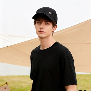 Men's casual black cotton baseball cap with gold logo shown on model in outdoor setting