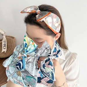 Detail of colorful floral print silk headband with orange edge on a fashion model