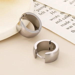Detailed close-up of wide polished titanium steel hoop earrings with glossy 18K gold finish