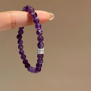 Macro view of purple amethyst beaded bracelet with sparkling zircon silver metal charm