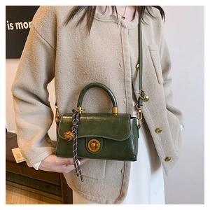 Detail of vintage dark green handbag featuring gold metal clasp and textured leather
