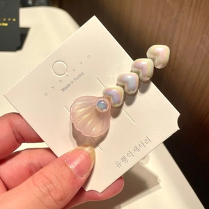 Detail of pink pearlescent shell hair clip with iridescent heart beads on metal grip