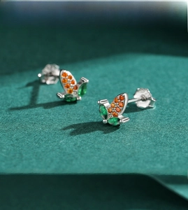 Macro detail of s925 silver butterfly earrings with orange and green zircon stones