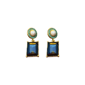 Vintage gold earrings with turquoise, pearls and rectangular blue gemstones on white background