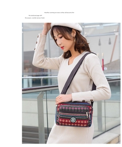 Detail of colorful striped canvas crossbody bag with multi-layer zippers and wide strap