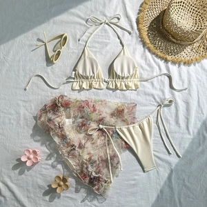 Detailed flat lay of a 3-piece bikini set with a floral mesh sarong and ruffles