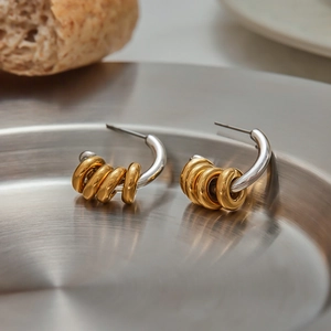 Detailed shot of two-tone C-shape earrings with gold rings on stainless steel tray