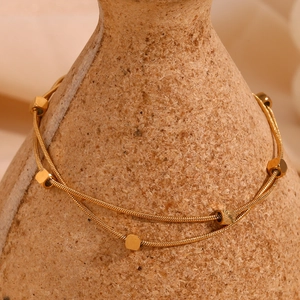 Macro detail of 18K gold-plated double-layer snake chain with geometric square beads