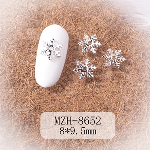 Macro shot of silver alloy snowflake nail charm sized 8x9.5mm on a white mannequin nail