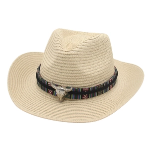 Detail of straw cowboy hat featuring ethnic woven band and silver metal bull skull ornament