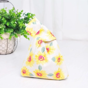 Close-up of Japanese cotton linen knot bag with yellow sunflower print and foliage