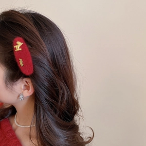 Close-up of red velvet hair clip with golden dog motif on woman wearing pearl necklace