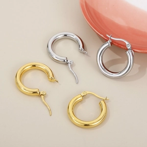 Close-up of thick gold and silver polished stainless steel hoop earrings with lever-back