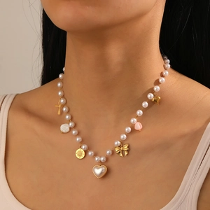 Close-up of pearl necklace with gold star, heart, shell and bow charms on model