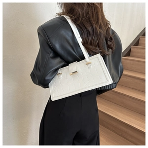 Close-up of a white croc-embossed underarm bag featuring a elegant gold metal buckle