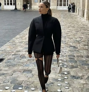 Outdoor street view of a slim fit black blazer paired with mesh leggings on a cobblestone street