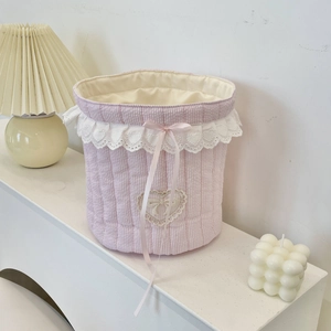 Detailed view of pink quilted fabric storage basket with lace trim and ribbon bows