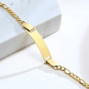 Detailed view of polished gold stainless steel identity plate on Figaro chain bracelet