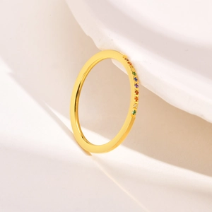 Detailed macro view of 1mm gold band ring with pavé-set colorful rainbow gemstones