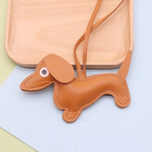 Close-up of brown litchi grain leather dachshund charm with stitching on a wooden tray