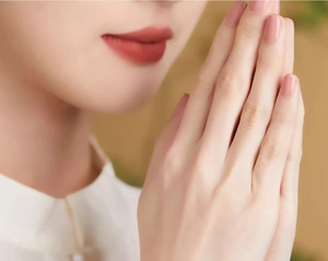 Close-up of hands in a meditative pose with natural wood prayer beads for spiritual practice