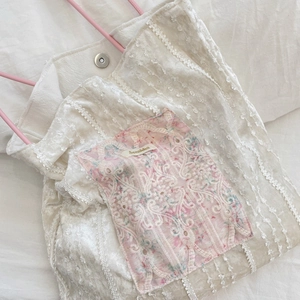 Gros plan sur la poche en dentelle florale et le fermoir magnétique du sac en toile