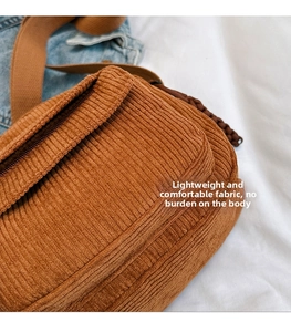 Close-up of brown corduroy crossbody bag texture with durable zipper and fabric strap