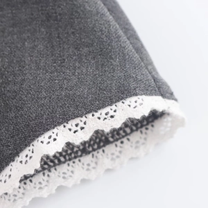 Close-up of grey knitted fabric texture with delicate white lace trim on the hemline