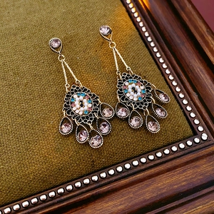 Detail of vintage flower earrings with pearls and rhinestones on green velvet fabric