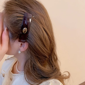 Elegant tortoiseshell hair clip with golden oval metal buckle shown on a model side profile