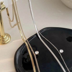 Close-up of double-layered gold snake chain necklace with a round zircon pendant detail