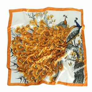 Detailed close-up of a peacock silk scarf featuring vibrant orange and blue feathers