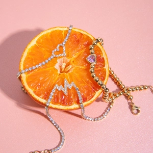 Elegantes 18K Gold und Silber Schmuckset mit Herzanhängern auf einer Orange frucht