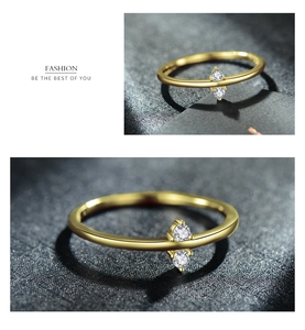 Close-up of a slim gold minimalist ring featuring two sparkling round-cut zircon stones