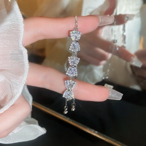 Close-up of luxury zircon bow bracelet in silver on wrist with adjustable pull-chain