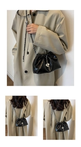 Detail view of black pleated bucket bag with metal chain strap and pearl pendant accent