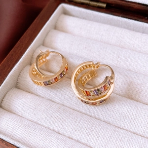 Detailed close-up of gold-plated cross-layer hoop earrings with colorful gemstones