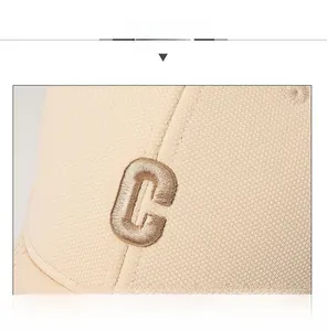 Detail of embroidered letter C on beige sandwich peaked cap with twill fabric texture