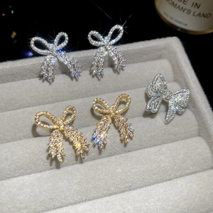 Close-up of sparkling bow earrings in gold and silver set on gray velvet display