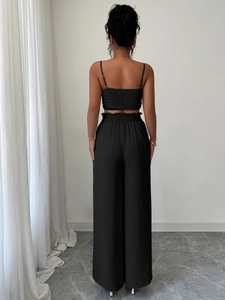 Vista posteriore del top nero con schiena arricciata e pantaloni a gamba larga a vita alta