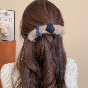 Detail of plush khaki hair claw with blue heart and bow on a half-up hairstyle