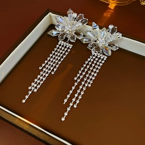 Detailed view of silver crystal flower earrings with long shimmering diamond tassels