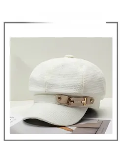 Detail of white newsboy cap featuring woven tweed texture and gold metal buckle detail