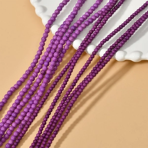 Macro detail of various purple round stone beads for DIY jewelry making on white ceramic