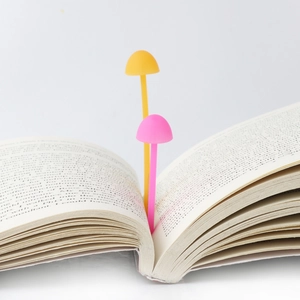 Close-up of pink and yellow silicone mushroom bookmarks placed inside an open book