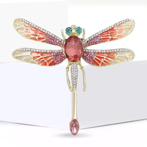 Macro shot of dragonfly brooch showing pink enamel wings and sparkling white rhinestones