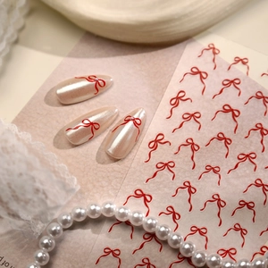 Autocollants pour ongles nœuds rouges sur faux ongles nacrés avec décor dentelle chic