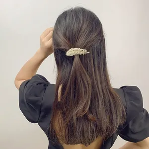 Macro shot of a gold feather hair clip with white pearls on long brunette hair