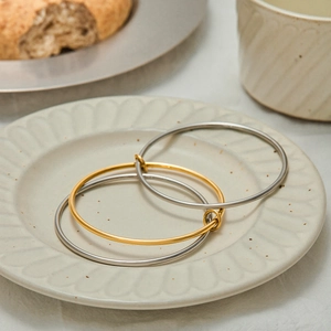 Minimalist stainless steel bangles set in gold and silver on a decorative ceramic plate